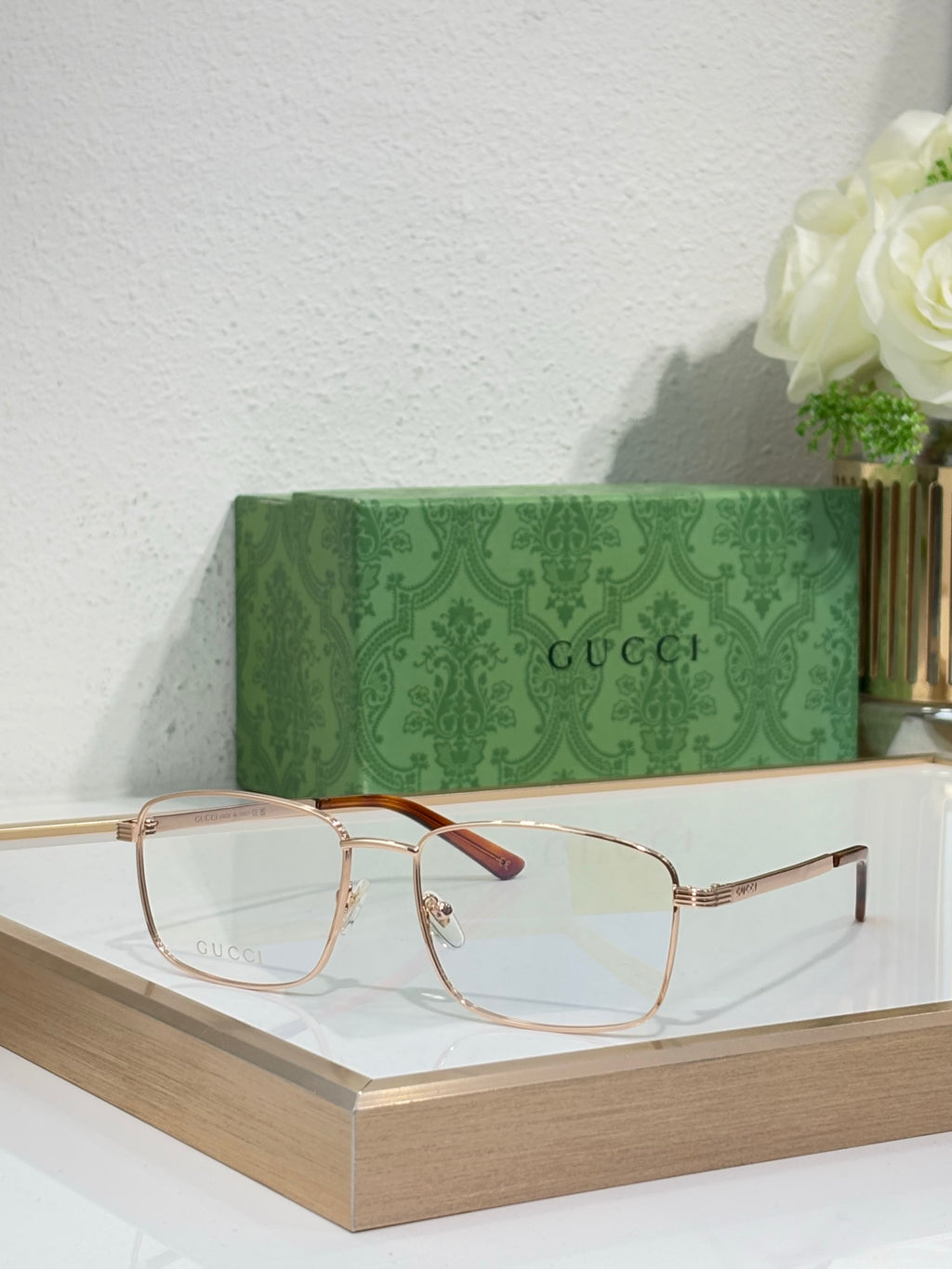 Eyeglasses with gold metal rectangular frame and burgundy-red accent on temple