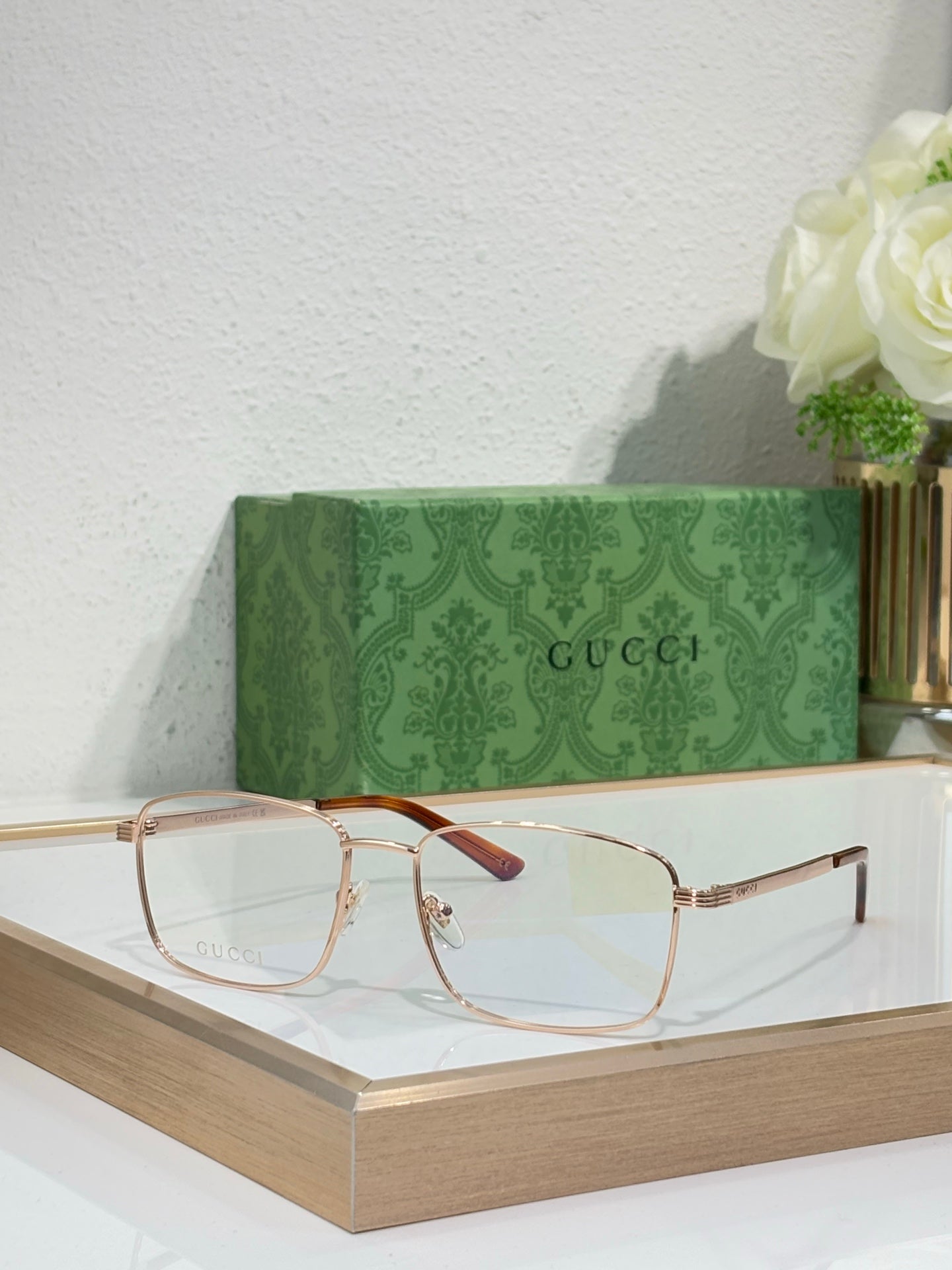 Eyeglasses with gold metal rectangular frame and burgundy-red accent on temple