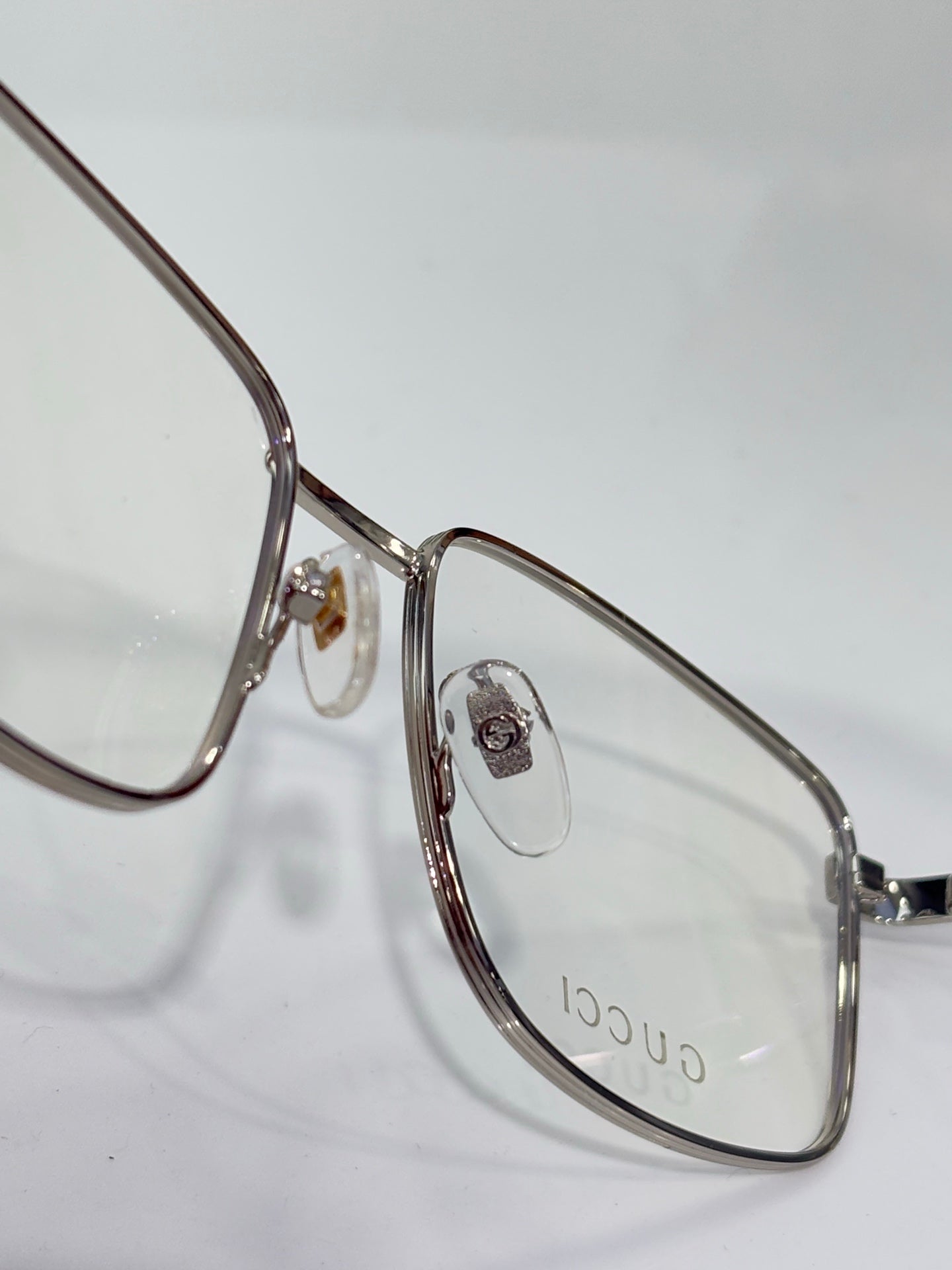 Eyeglasses close-up with silver metal oval frame and small logo emblem at hinge