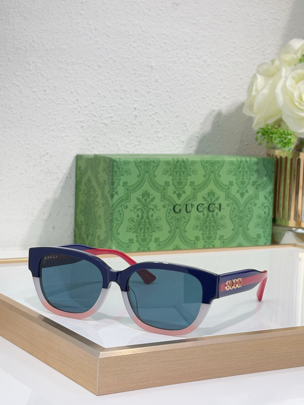 Gucci sunglasses with black frames, blue lenses; red accents on the temples.