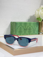 Gucci sunglasses with black frames, blue lenses; red accents on the temples.