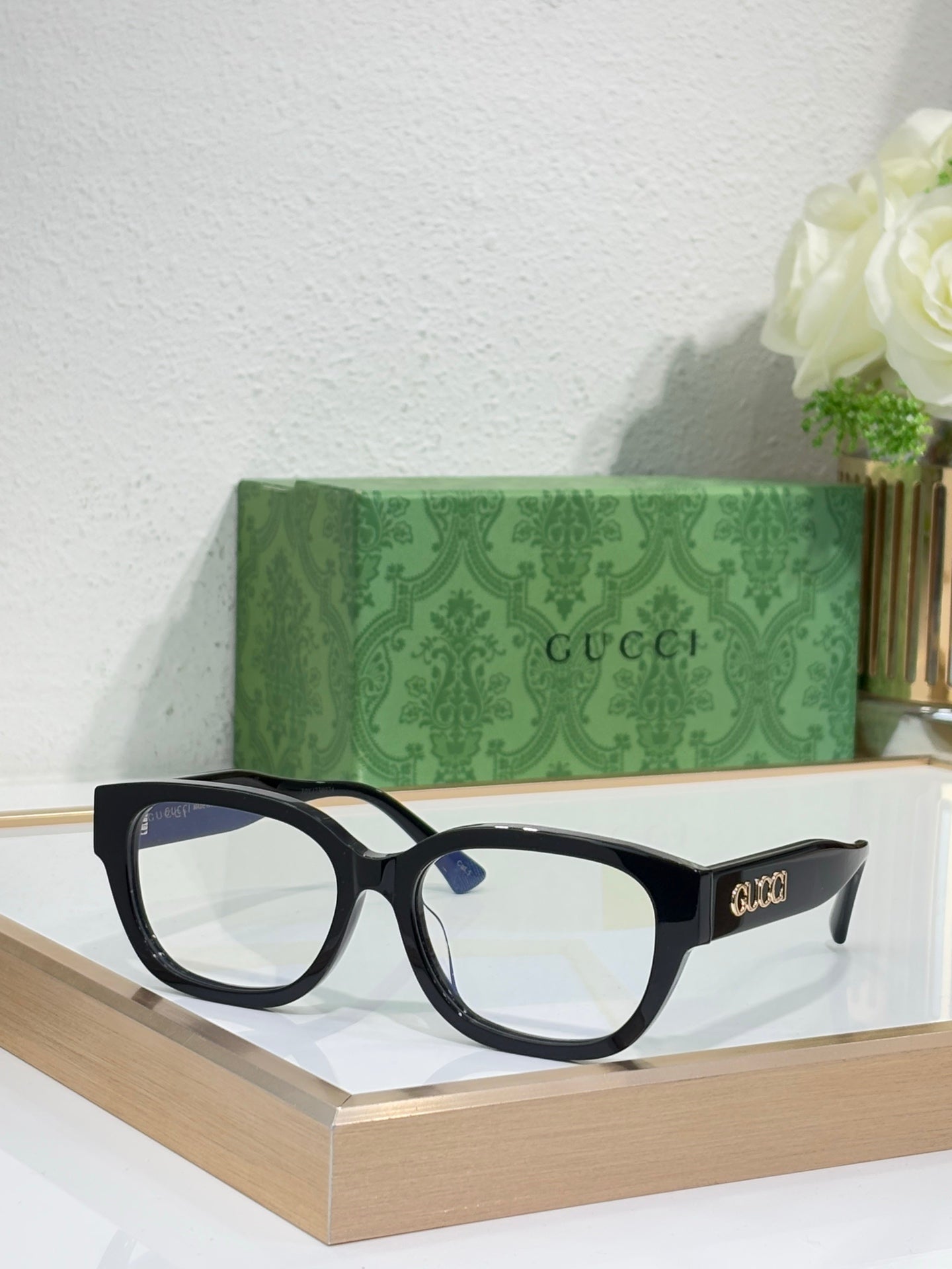 Gucci eyeglasses with black frames and clear lenses; squared, slightly rounded design.