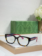 Gucci eyeglasses with black frames and clear lenses; blue and burgundy temple accents.