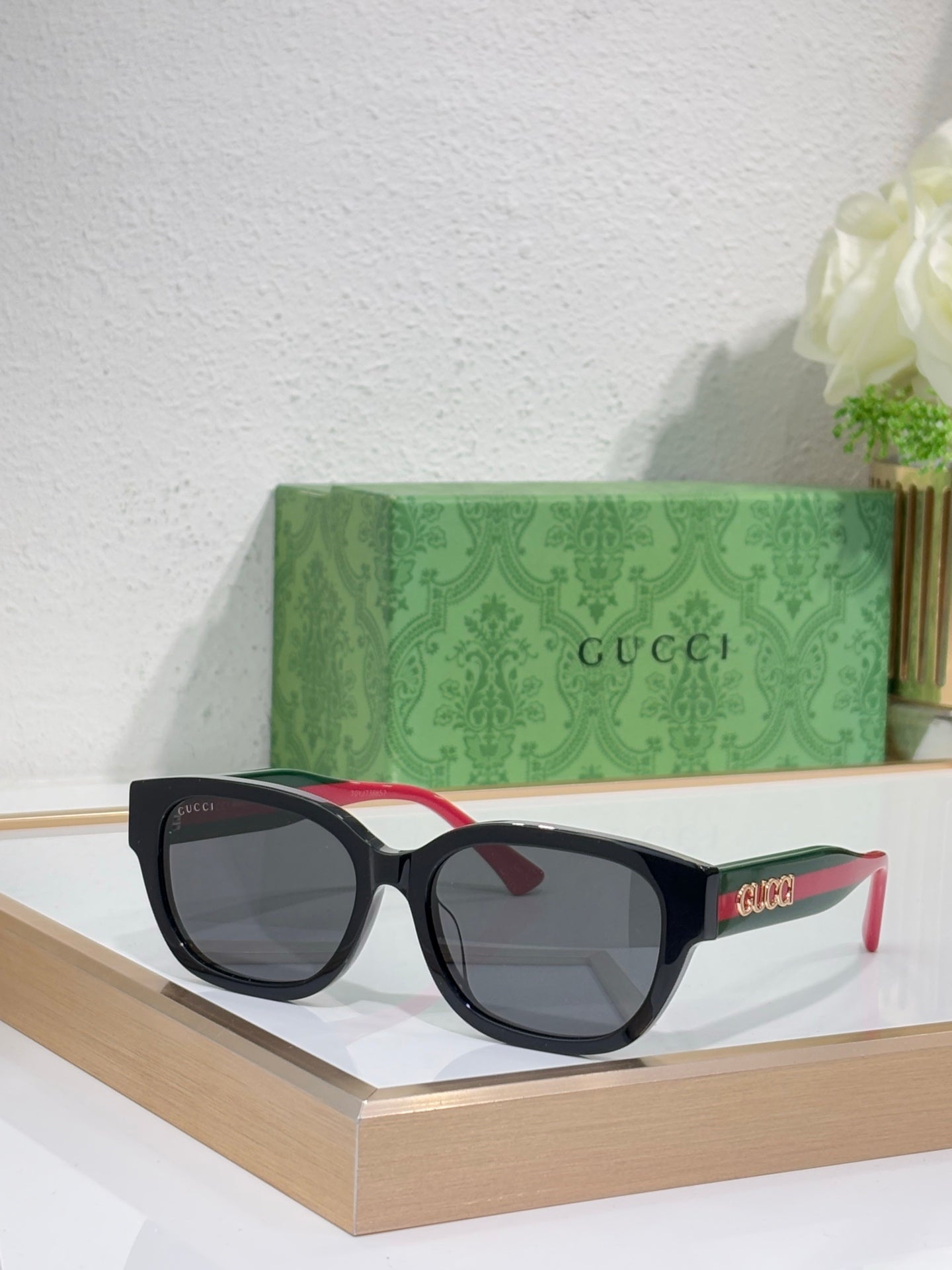 Gucci sunglasses with black frames, dark lenses; red and green temple accents.