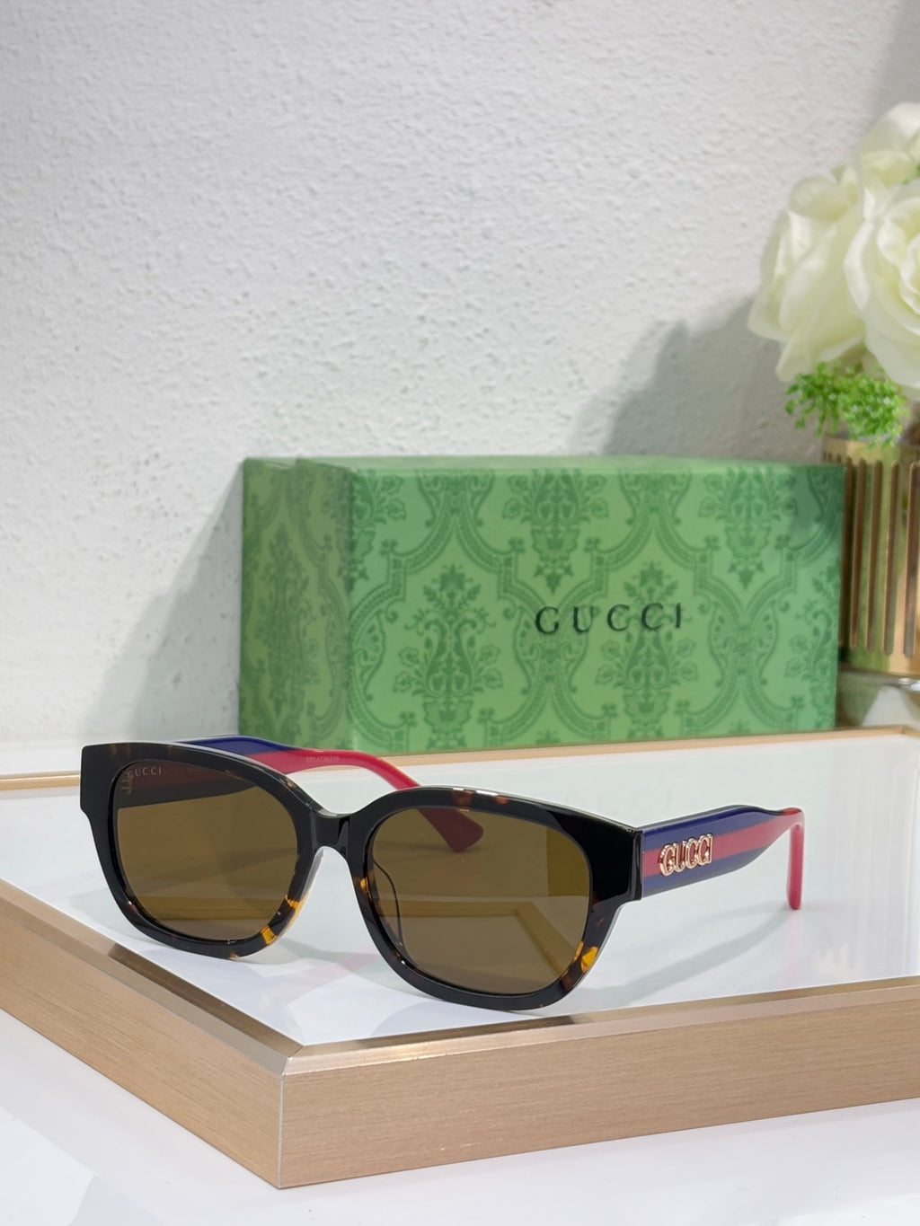 Gucci sunglasses with black frames, warm brown lenses; squared style with thin arms.
