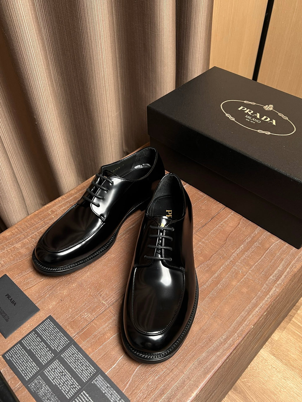 Prada black leather lace-up shoes in two angles, with black laces and glossy uppers