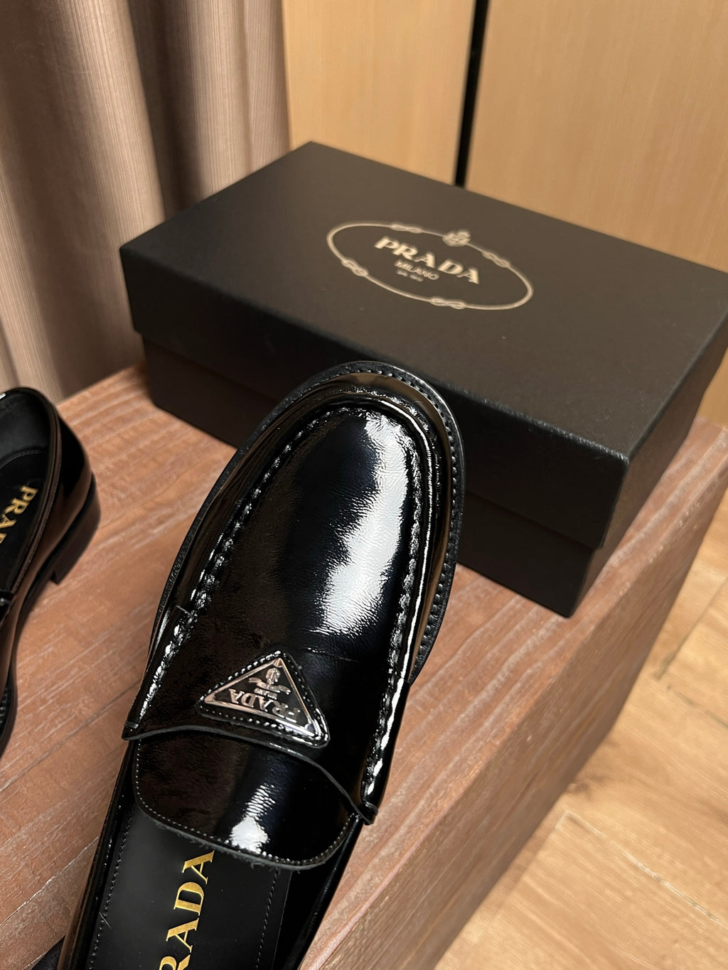 Black patent leather loafer close-up with triangular emblem and Prada lettering