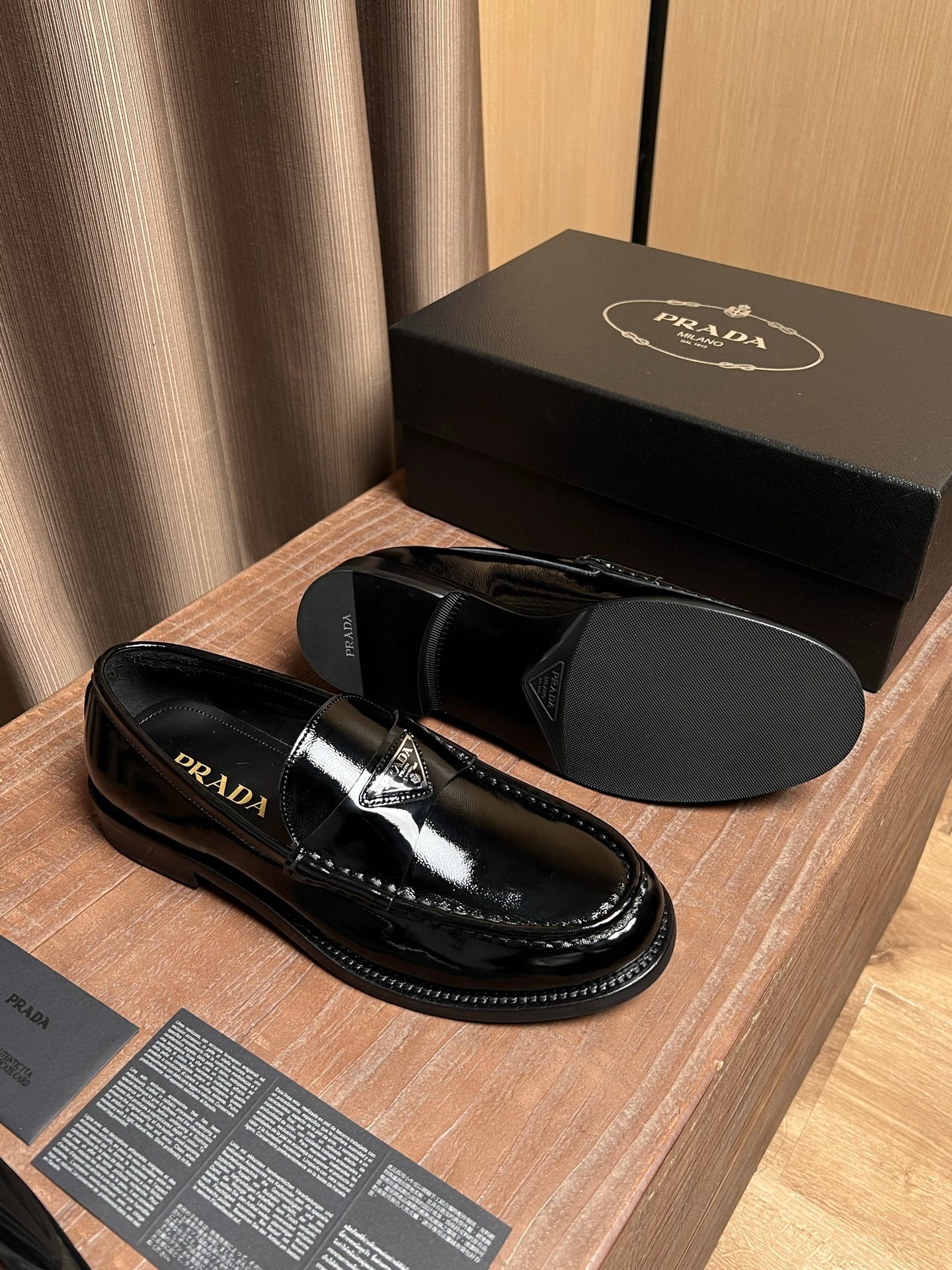 Black patent leather loafers with Prada logo on strap and glossy finish