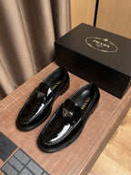 Black patent leather loafers with decorative triangular emblem on the vamp