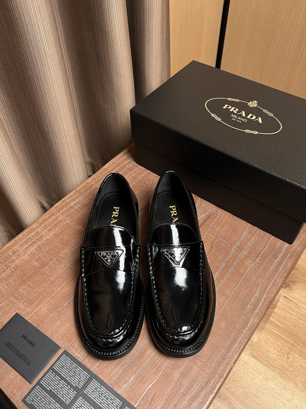 Black patent leather loafers with Prada logo on the vamp