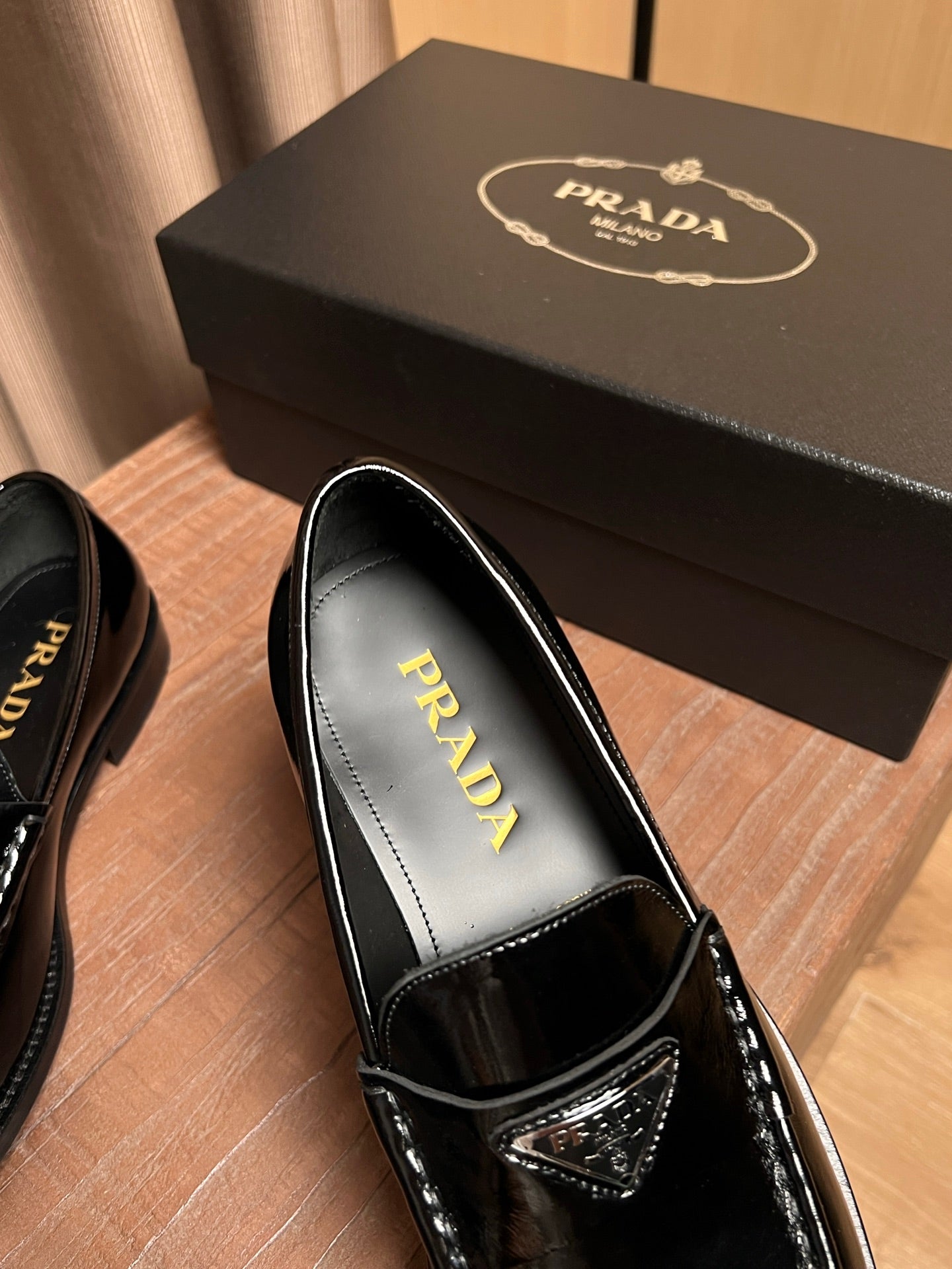 Black patent leather loafer showing Prada gold logo on the insole