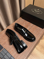 Black patent leather loafer with gold buckle strap and ridged sole edge