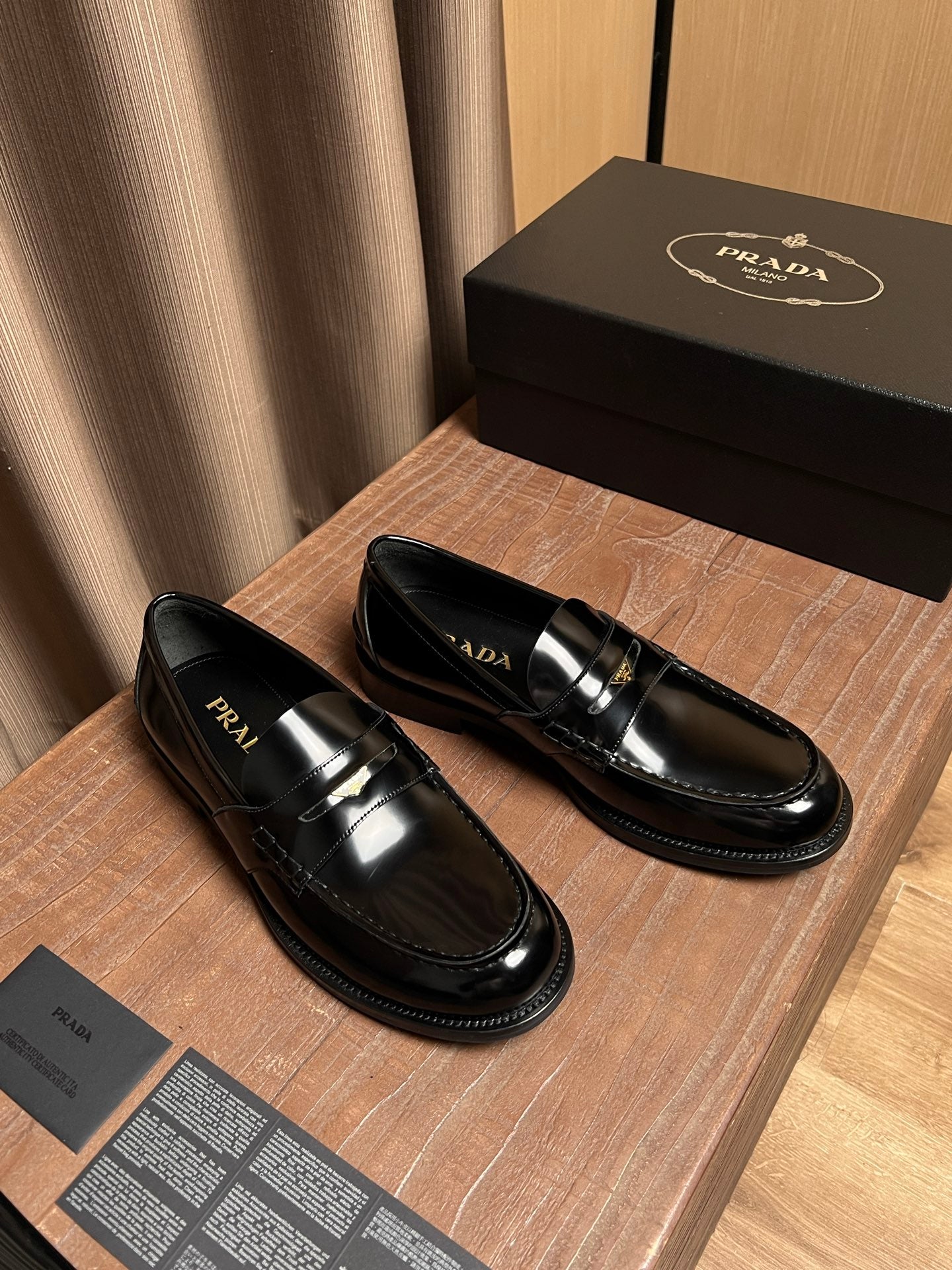 Black patent leather loafers with metal bar detail and Prada logo, side view