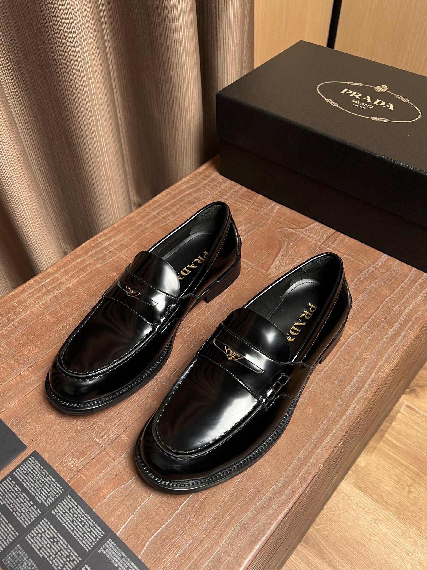 Prada black patent leather loafer with stitched strap and gold buckle