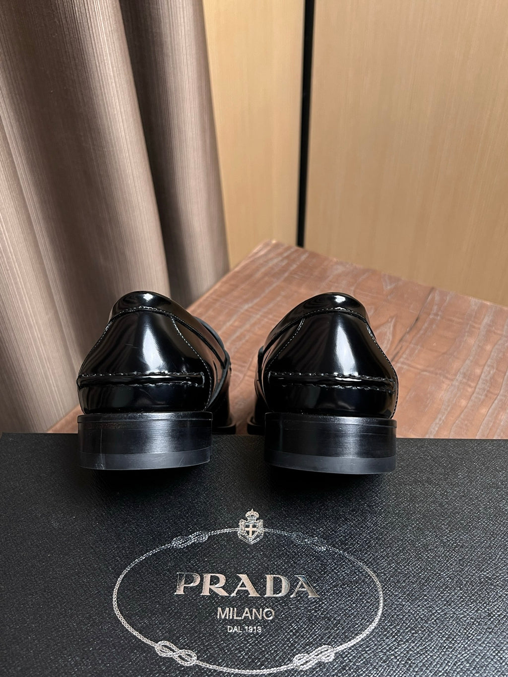 Black patent leather loafers, heel backs visible with Prada Milano logo