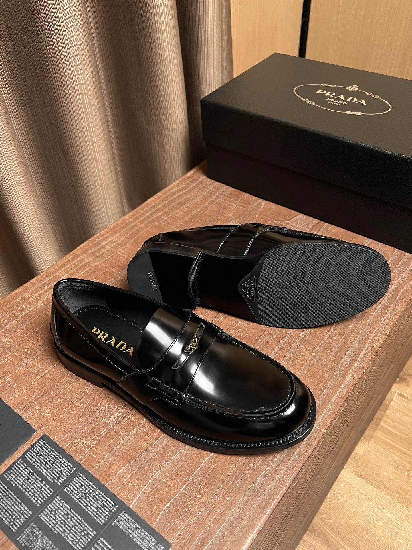 Black leather Prada slip-on loafers with gold-tone strap, top view
