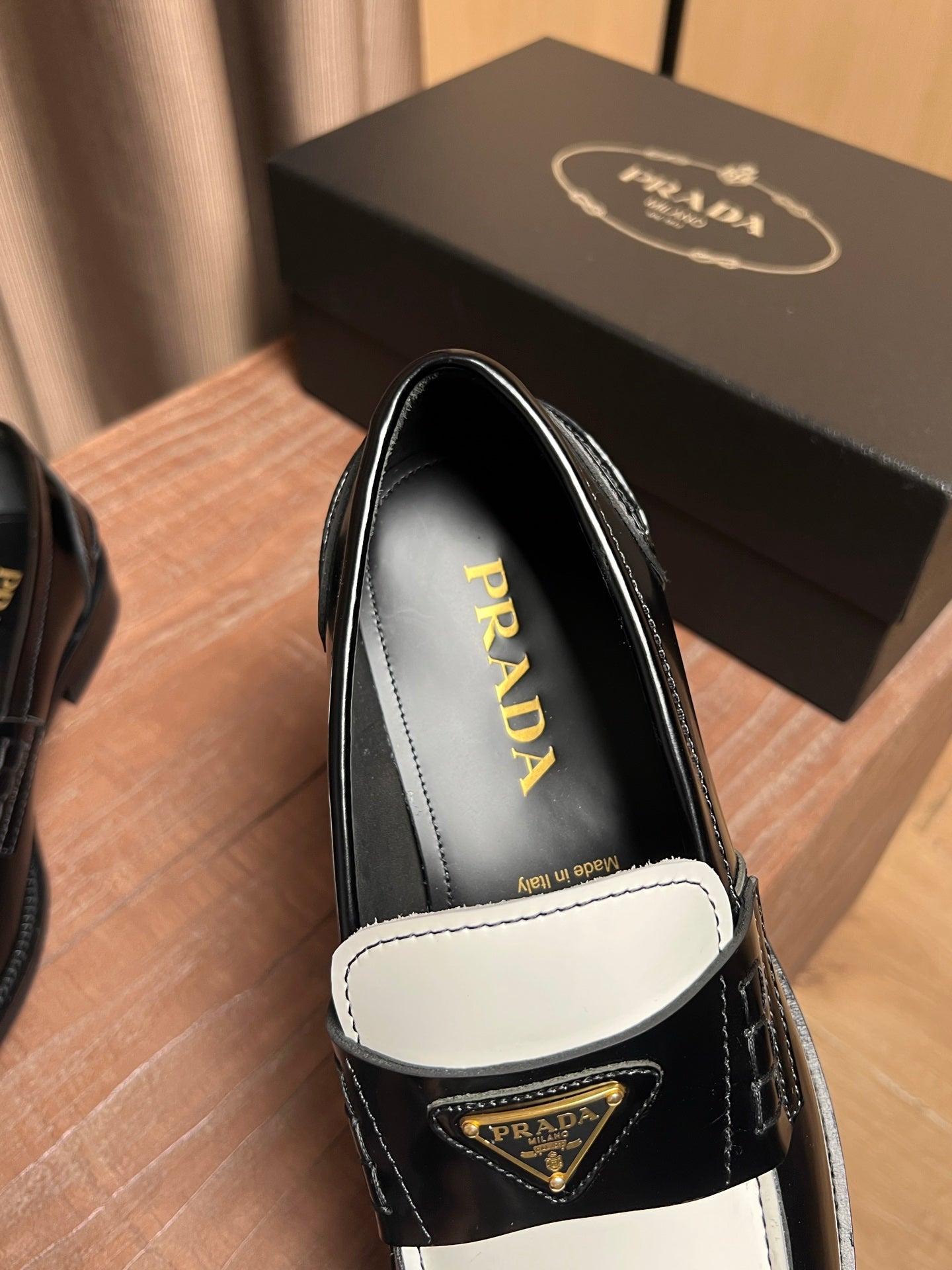 Prada loafer close-up: black leather with white apron and gold triangle logo