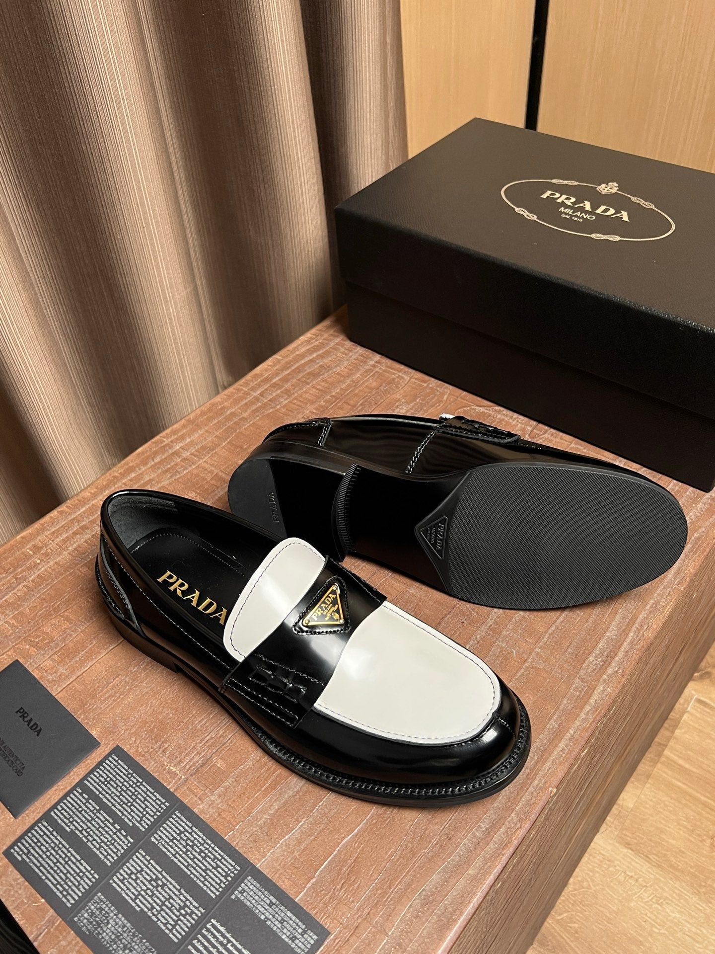 Prada unisex loafers with black-and-white uppers and gold logo emblem