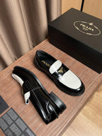 Prada black leather loafers with white trim and gold-triangle logo