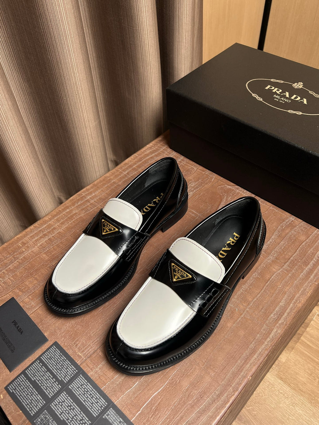 Prada loafers with black uppers and white apron, gold logo detail