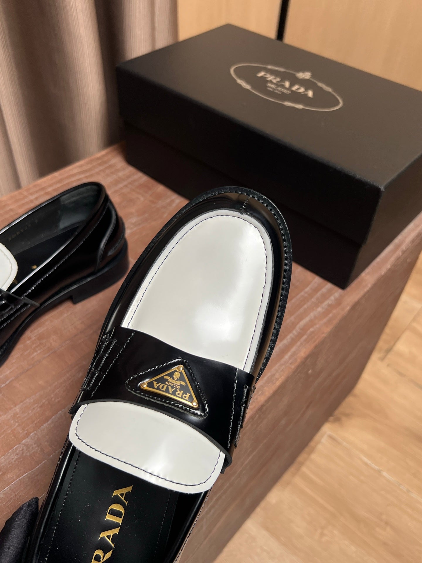 Prada loafer top view with white panel, black leather, and gold triangle emblem