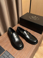 Black leather Prada loafers pair with gold emblem on the vamp