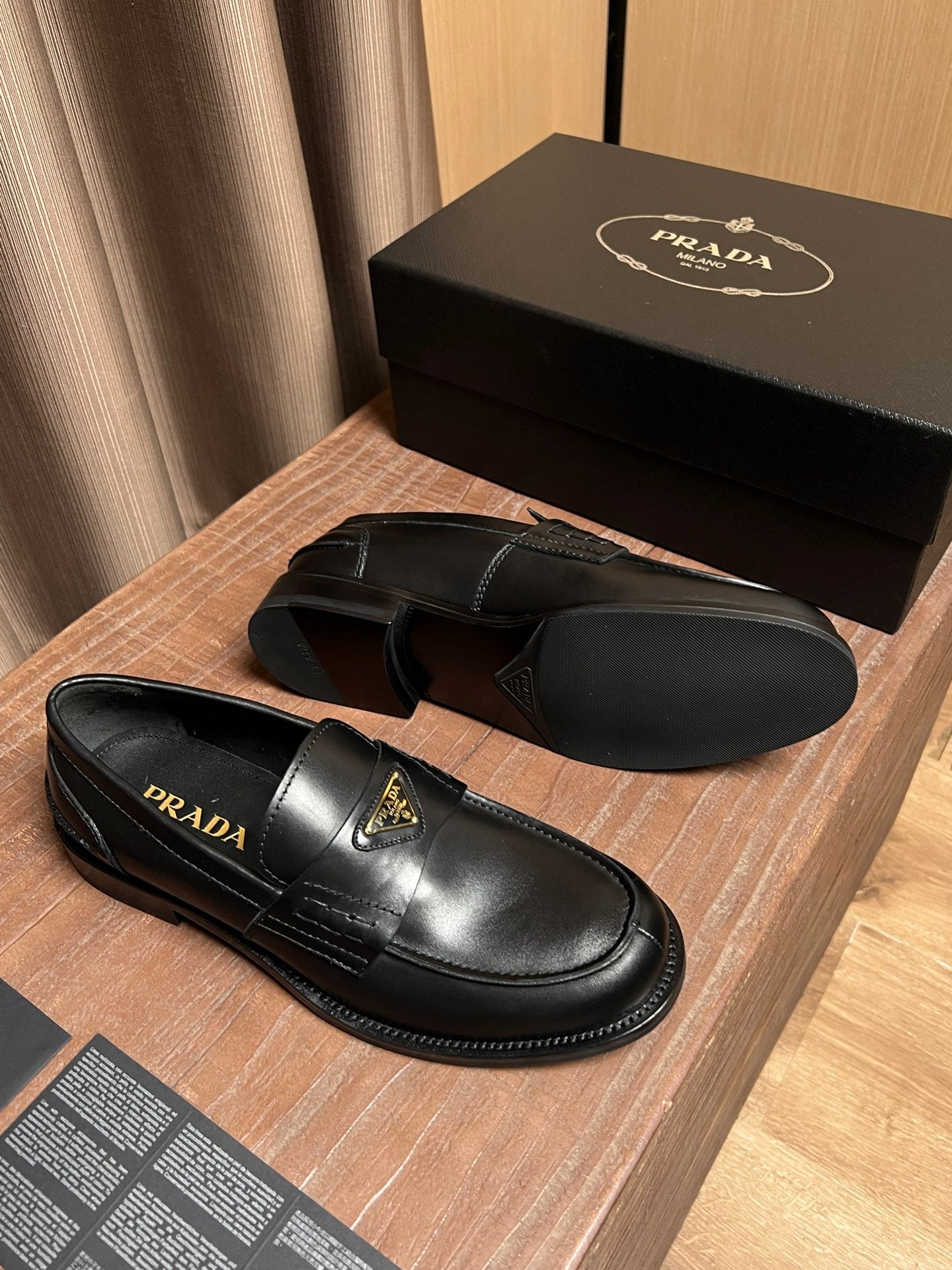 Black leather Prada loafers with gold triangle emblem and slip-on loafer silhouette