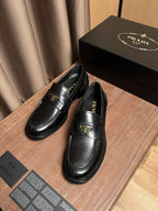 Black leather Prada loafers with gold triangle emblem on the front