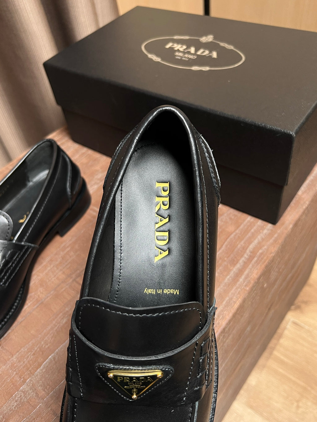 Black leather Prada loafer close-up with PRADA insole lettering and gold emblem