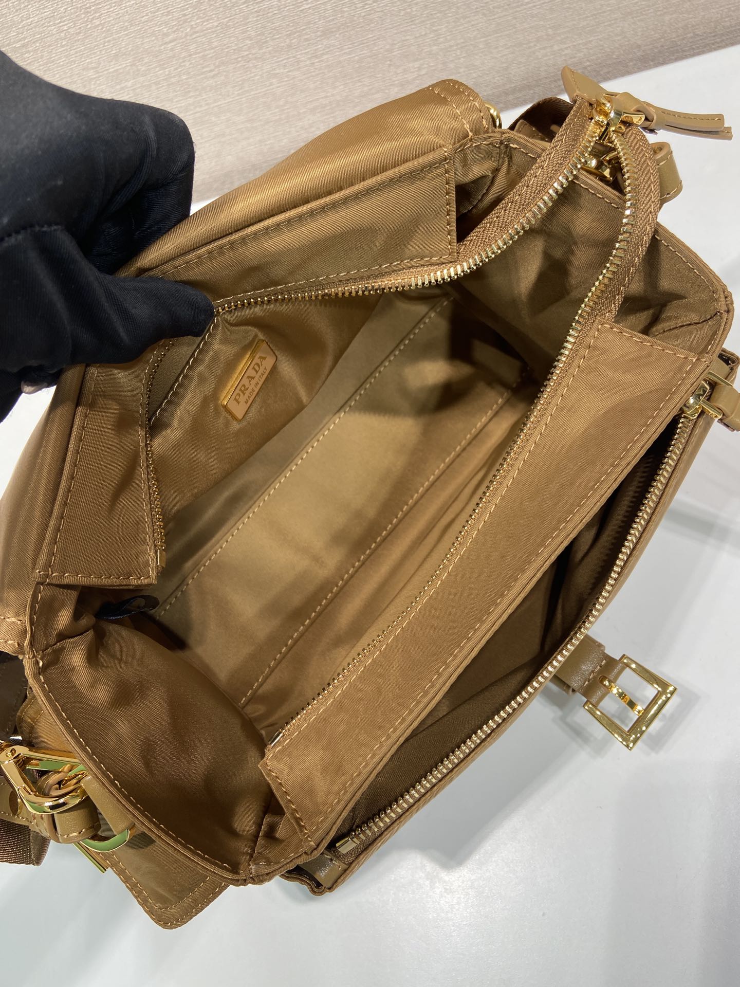 Prada tan bag interior view with zipper, stitched panels, and gold hardware