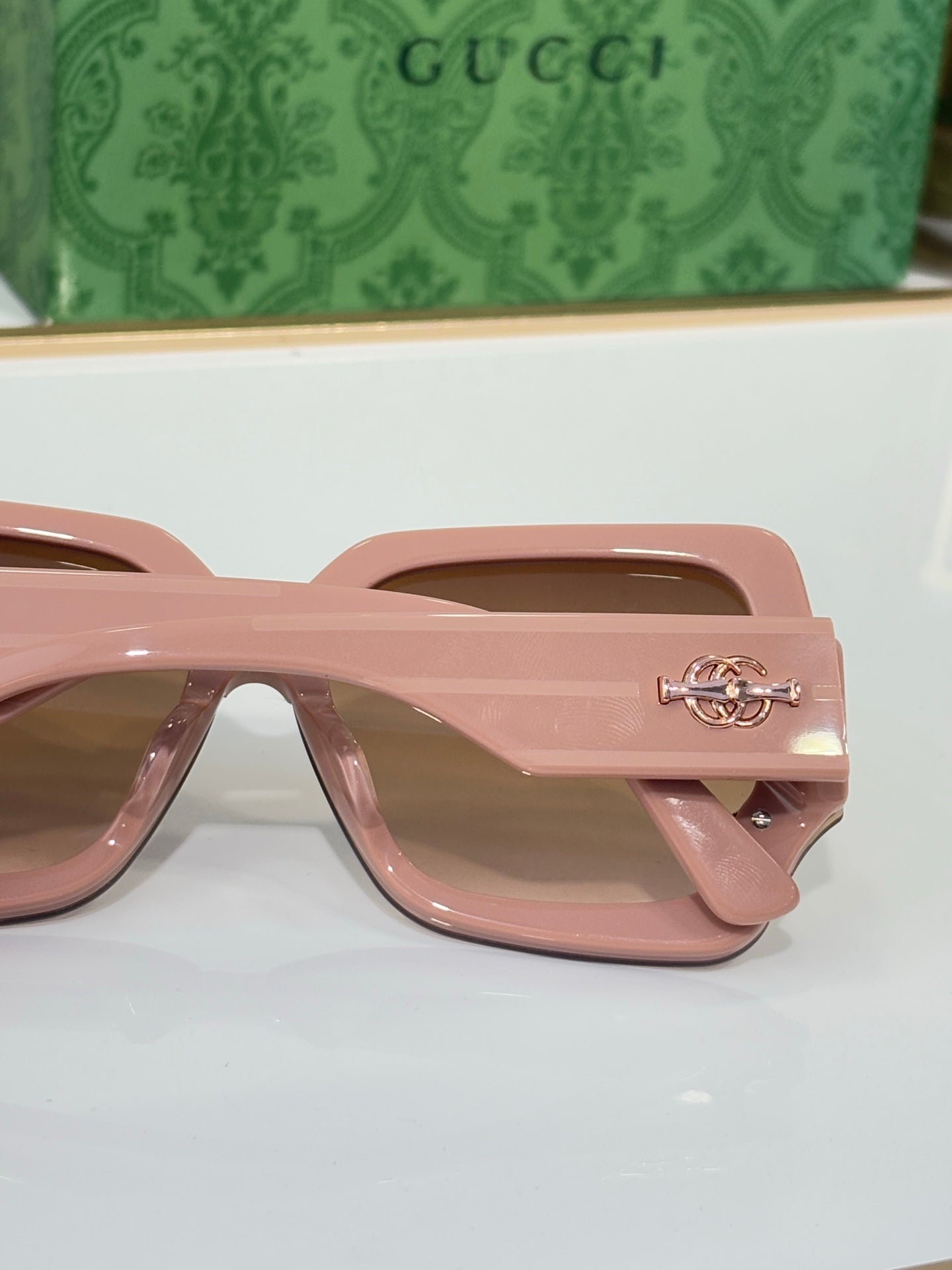 Pink oversized square sunglasses with brown-tinted lenses and metal side logo