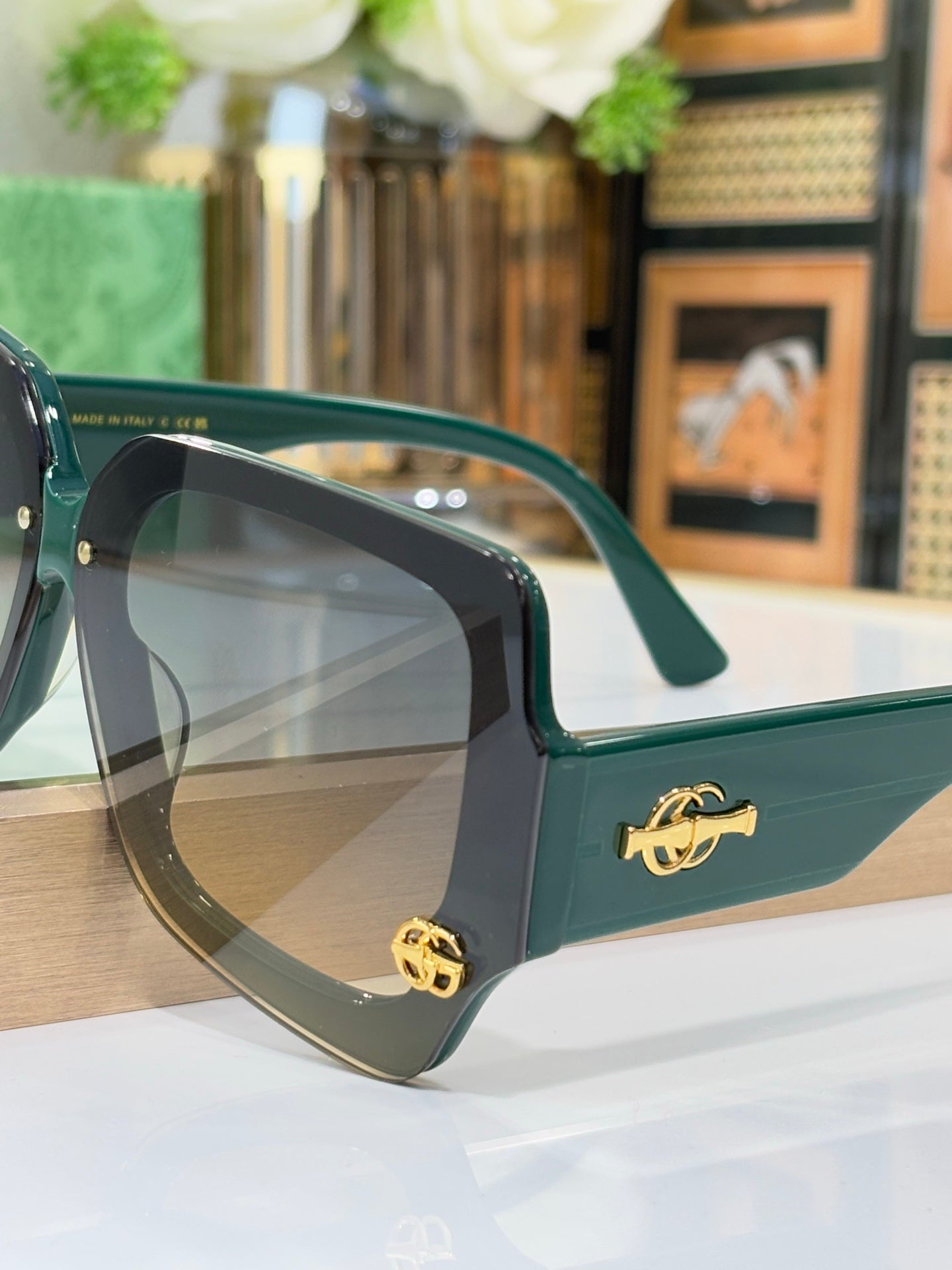 Teal square sunglasses with clear dark lenses and gold logo detail on temple