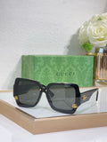 Dark square sunglasses with black frame and smoky gray lenses, gold logo detail