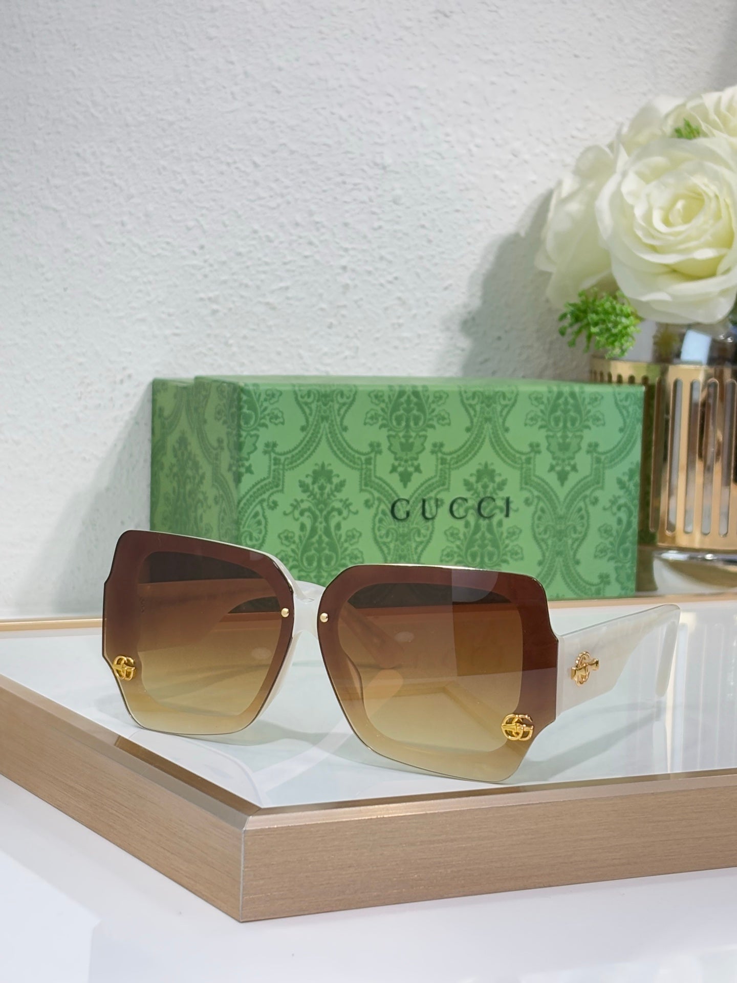 Oversized square sunglasses with brown frame and amber-tinted lenses, gold logo detail