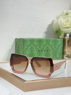 Oversized square sunglasses with pink frame and brown-tinted lenses, gold logo detail