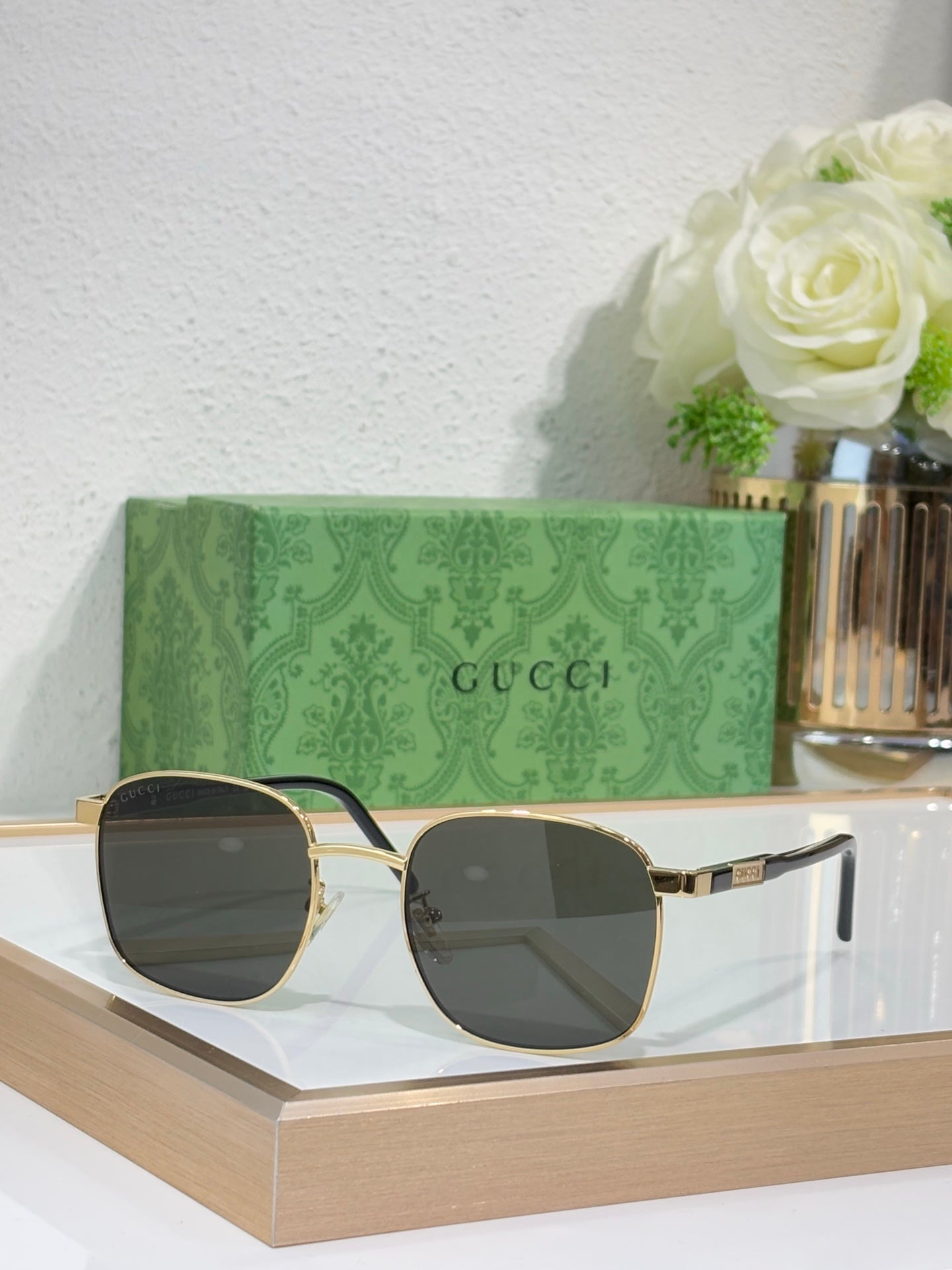 Gucci sunglasses with dark tinted lenses and black-and-gold temples