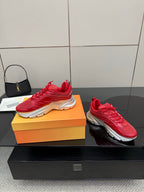 Red lace-up sneakers with chunky sole on an orange shoebox