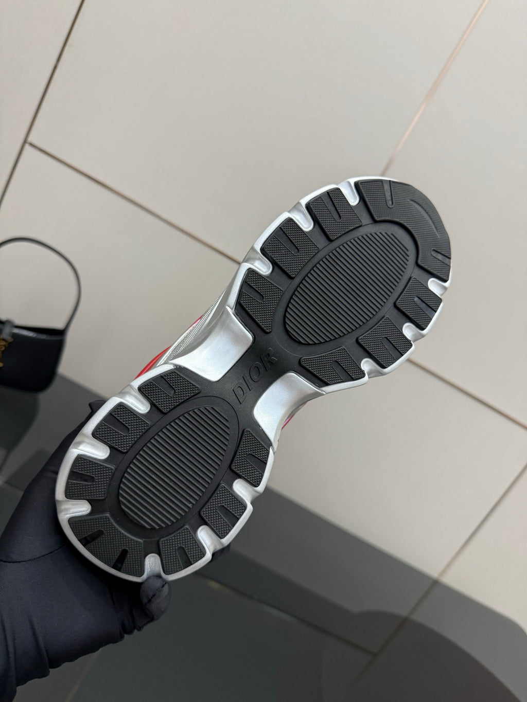 Shoe outsole view: sneakers with textured black tread and silver trim