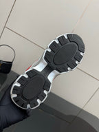 Shoe outsole view: sneakers with textured black tread and silver trim