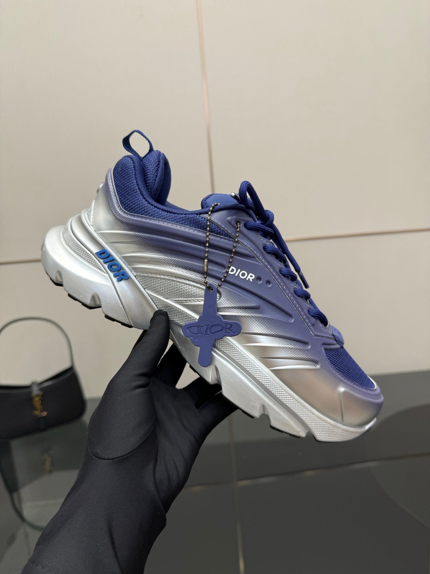 Blue and silver sneaker held up, lace-up design and logo detail on side