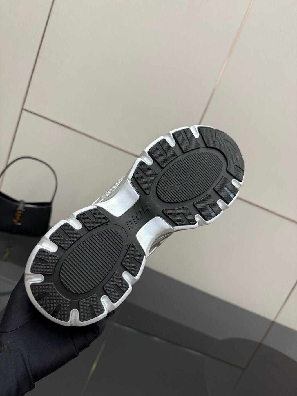 Sneaker outsole view with dark tread pattern and silver trim edges