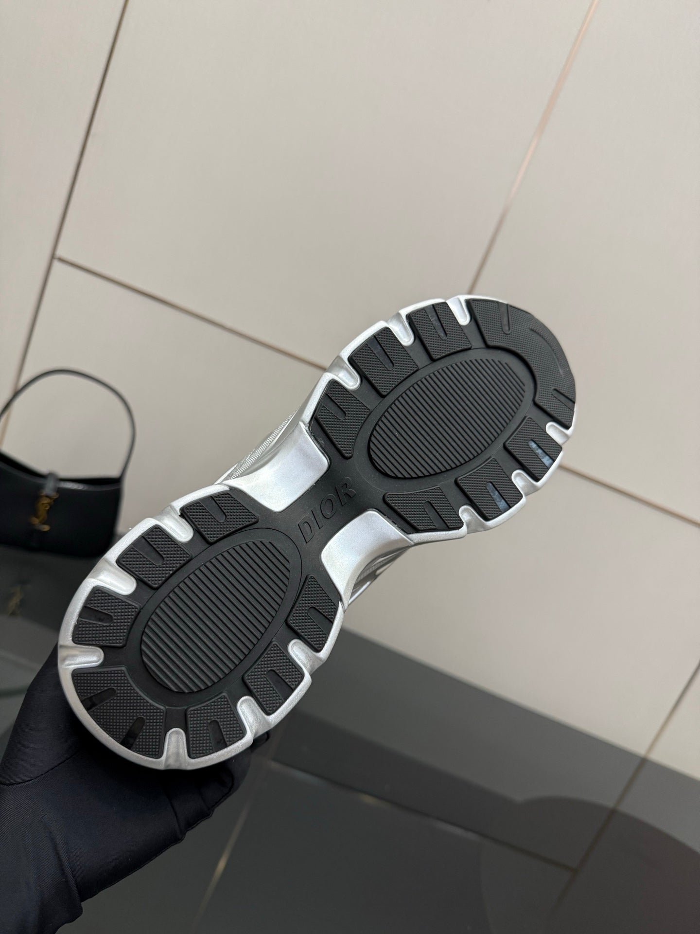 Sneaker outsole view with dark tread pattern and silver trim edges