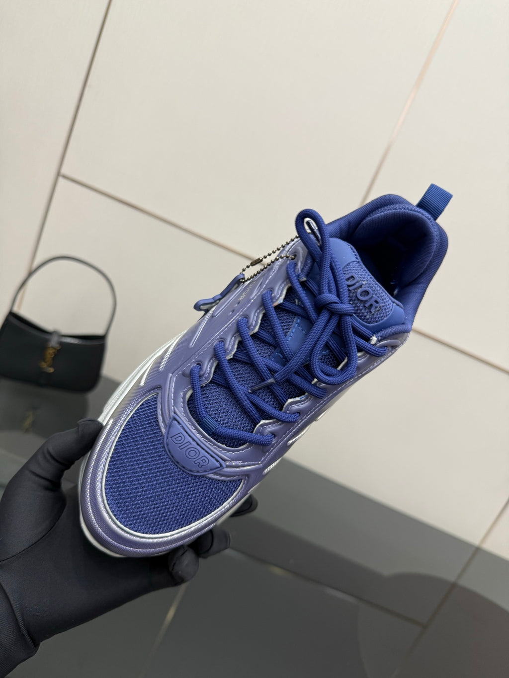 Blue lace-up runner sneaker held in hand with textured sole tread