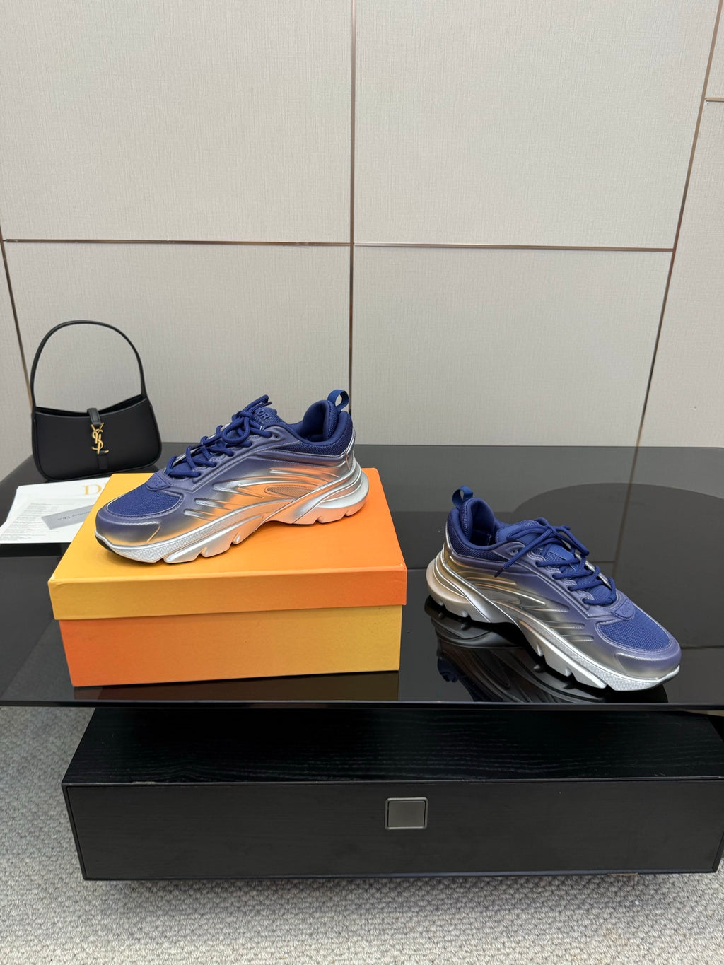 Blue lace-up sneakers with silver soles, displayed on an orange shoe box