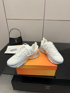 Pair of white low-top sneakers with white laces and Dior logo detail on side