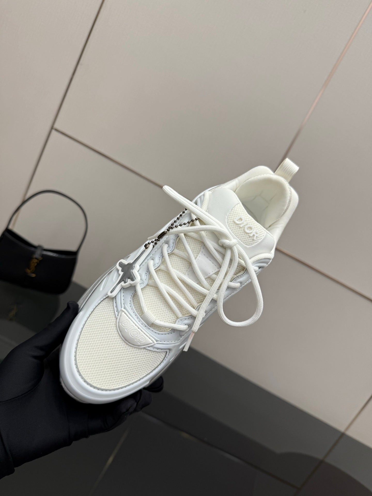 Close-up of white low-top sneaker with white laces and Dior lettering on tongue