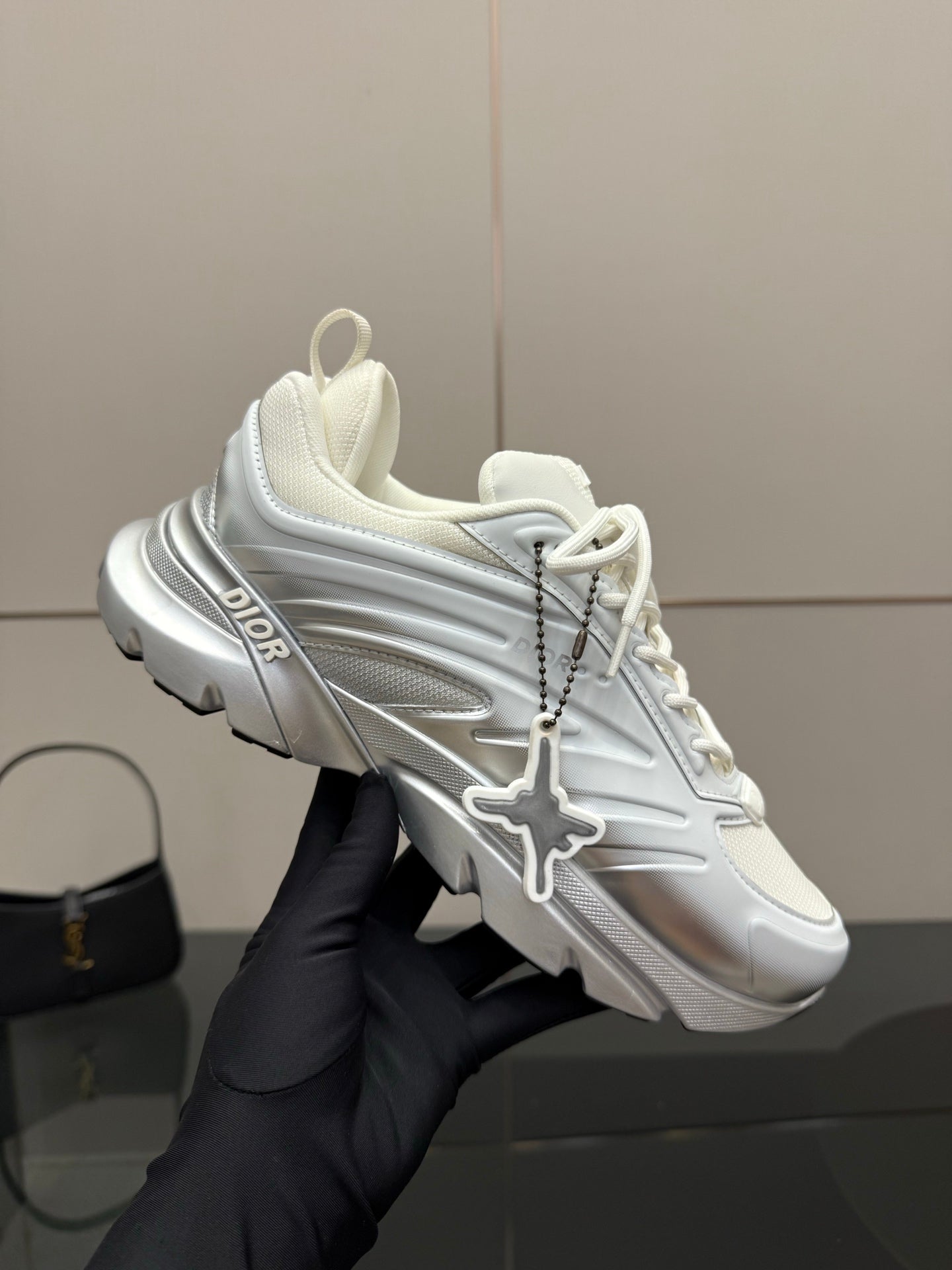 Hand-held white and silver low-top sneaker with Dior logo and cross strap detail