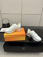 White low-top sneakers with white laces, chunky sole, and Dior branding detail