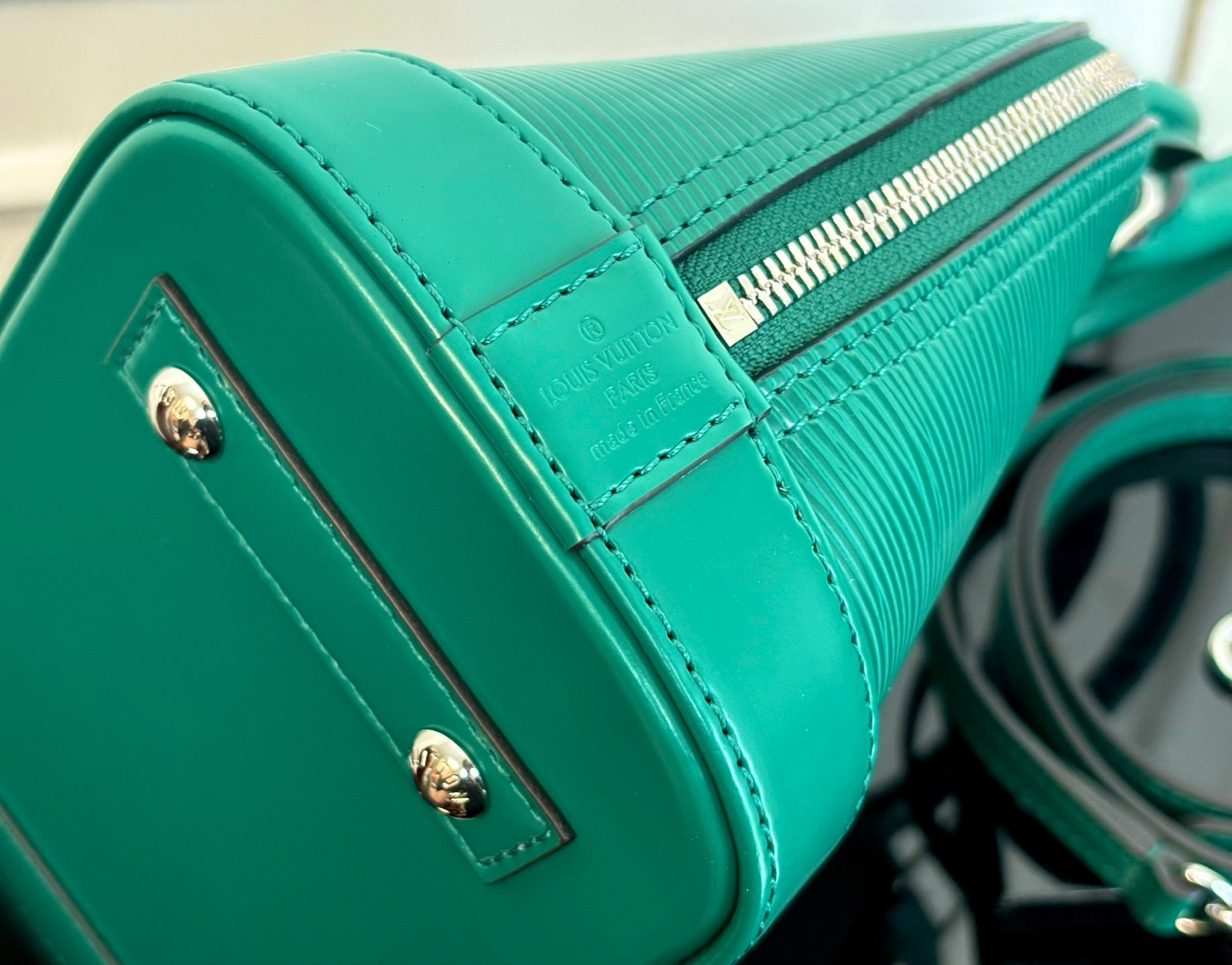 Louis Vuitton green handbag close-up of stitched side panel and silver-tone studs