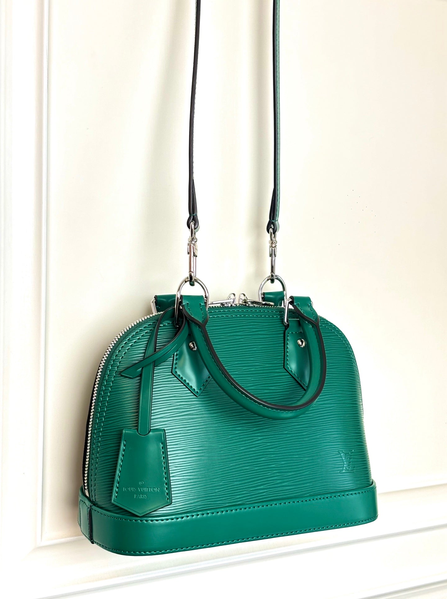 Louis Vuitton green handbag with two straps, front logo charm, and zip closure